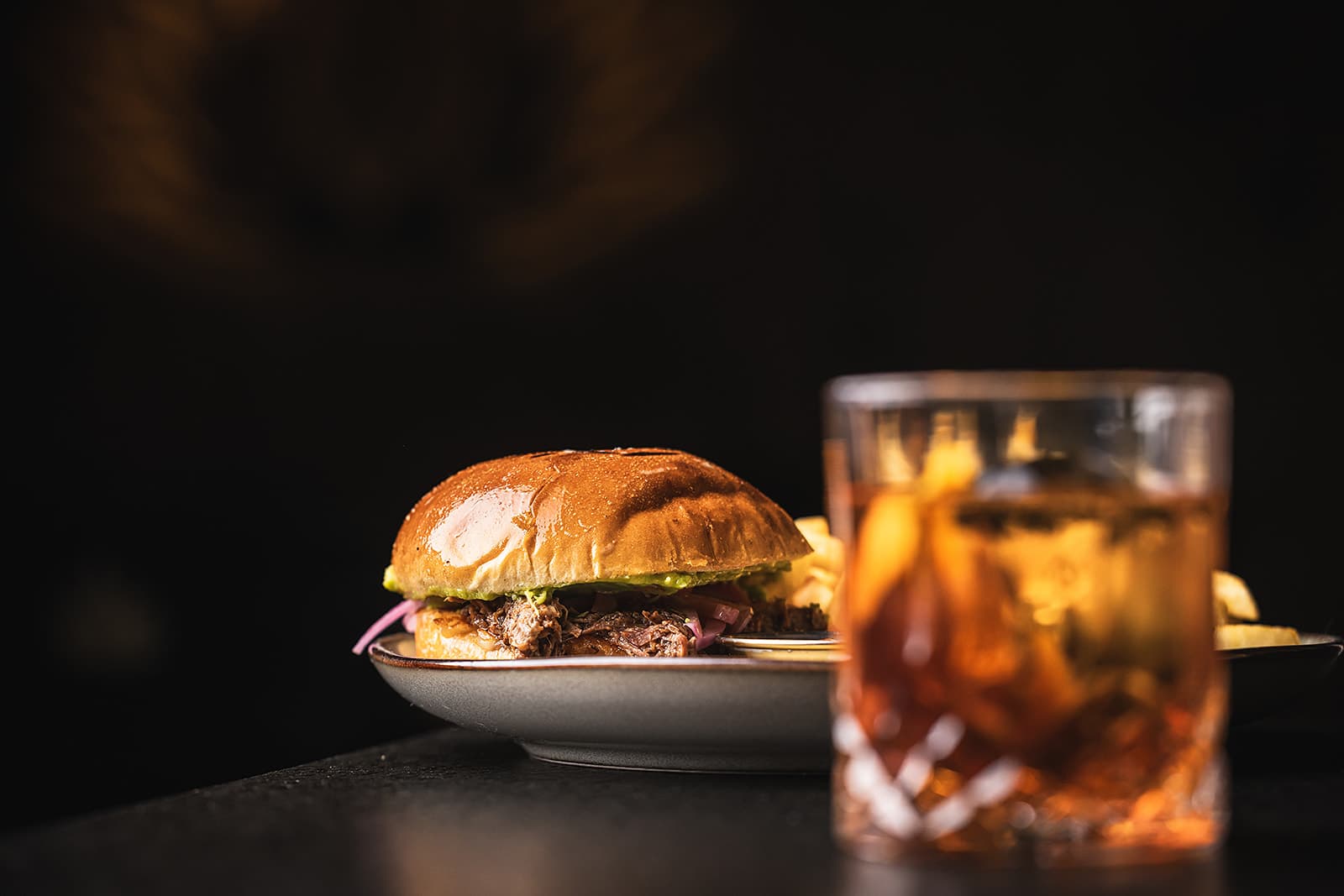 Birria torta with fries and an amber cocktail