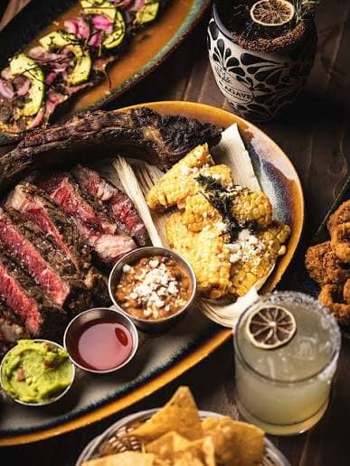 Sliced Tomahawk steak served with Mexican street corn and cocktails at Miel de Agave